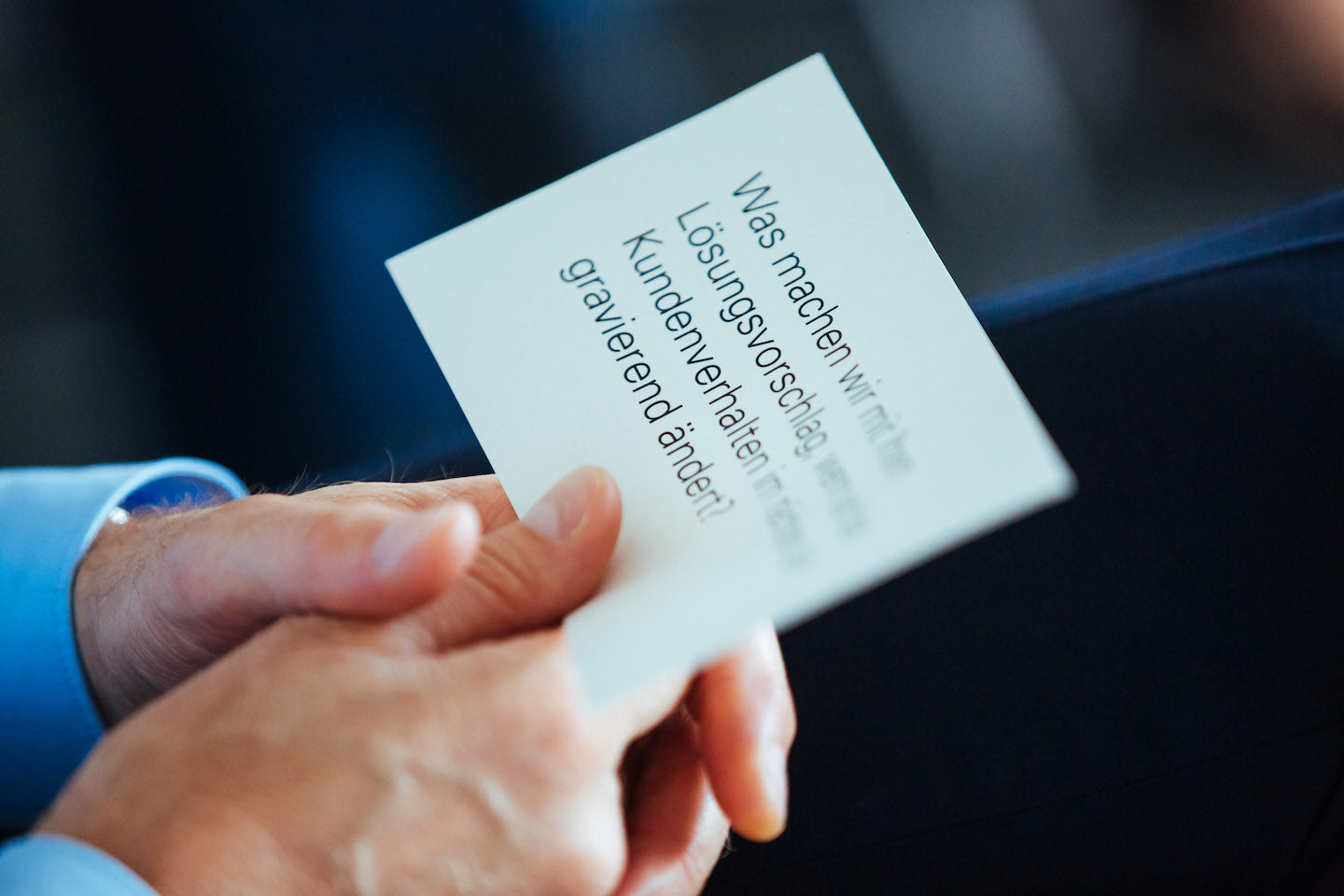 Eine Person hält eine Karte mit der Frage „Was machen wir mit Ihrem Lösungsvorschlag, wenn sich das Kundenverhalten nicht gravierend ändert?“ in den Händen.